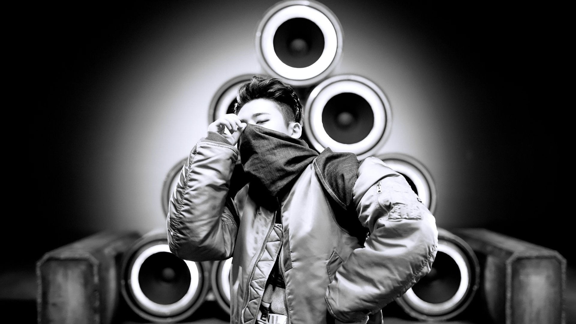 HD desktop wallpaper featuring a monochrome image of a person with iKON style, posing in front of an array of speakers.