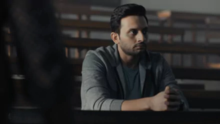 HD desktop wallpaper featuring a contemplative person from Tandav, set in a dimly lit room.