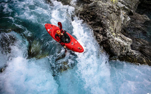 HD wallpaper featuring a kayaker navigating turbulent rapids in a red kayak.