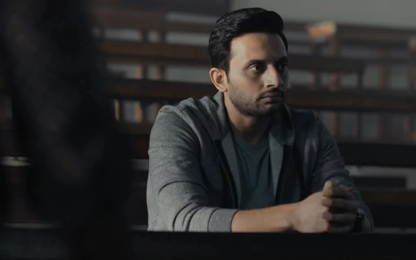 HD desktop wallpaper featuring a contemplative person from Tandav, set in a dimly lit room.
