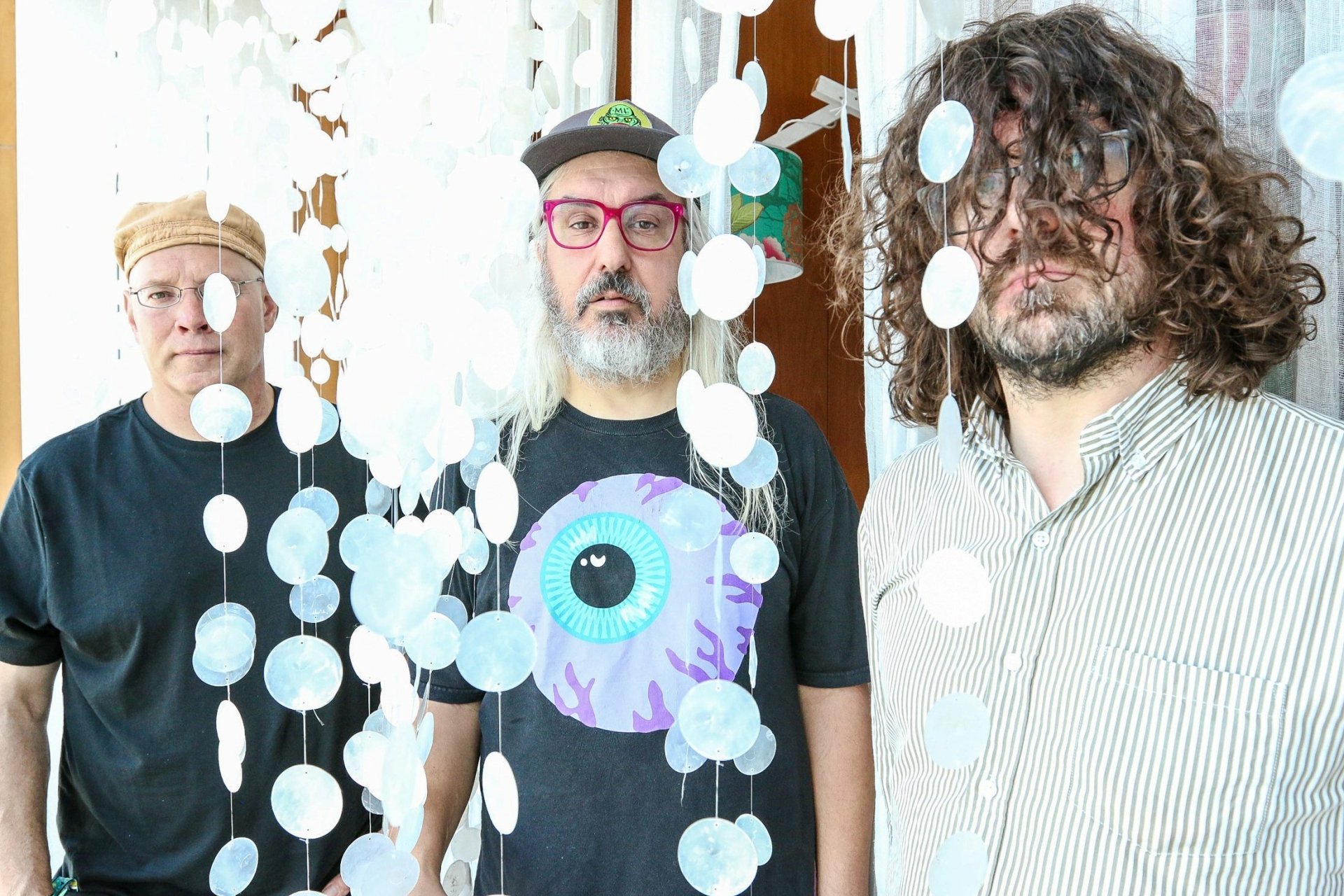 HD wallpaper featuring three members of the band Dinosaur Jr. standing in front of a decorative hanging backdrop.