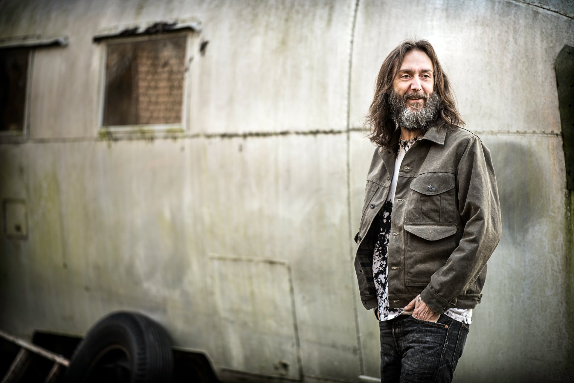 Chris Robinson of The Black Crowes poses with a smile against a weathered backdrop for an HD desktop wallpaper.