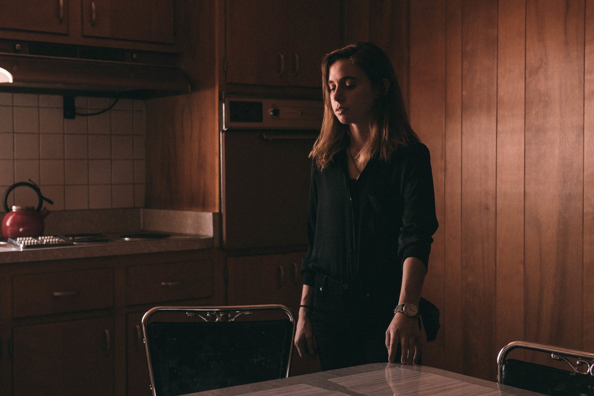 HD wallpaper of a person in a dimly lit kitchen with wooden panels, suited for desktop background, tagged with Julien Baker.
