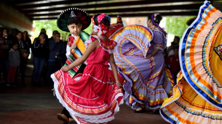 Colorful Mexican dance performance, with dancers in traditional dresses and a sombrero, as a vibrant HD desktop wallpaper.