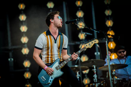 HD wallpaper featuring a Royal Blood band member playing guitar on stage with atmospheric stage lighting.