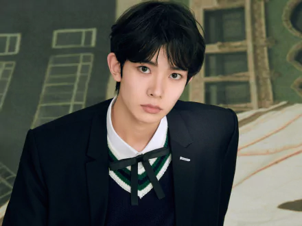 2K Quad HD PC desktop wallpaper: ENHYPEN music–themed portrait of a young man in a dark blazer and tie against a muted green architectural backdrop.