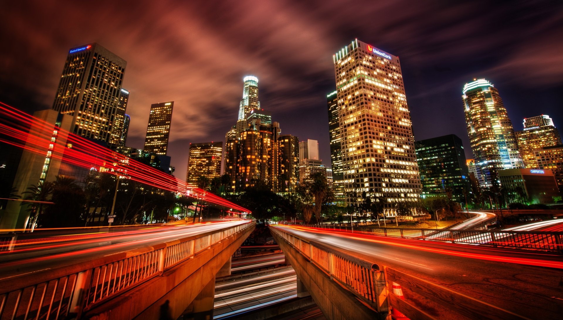 Time-lapse night view of Los Angeles city skyline with illuminated skyscrapers and light trails, captured in 4K Ultra HD for a vibrant desktop background.