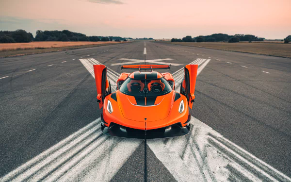 A vibrant orange Koenigsegg Jesko supercar with doors open, positioned on an empty runway at sunset, captured in 8K Ultra HD for PC desktop wallpaper.