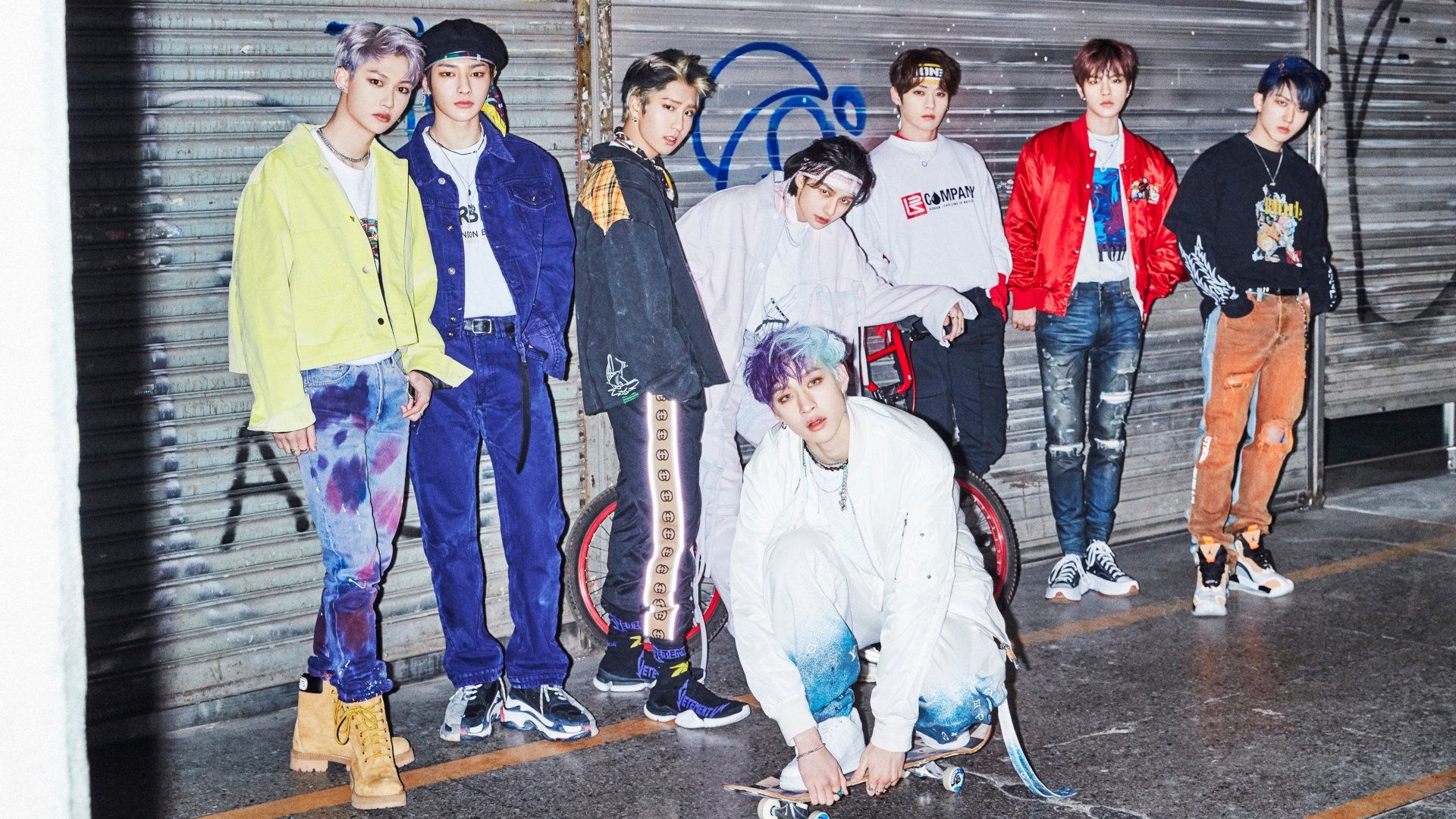 Stray Kids K-pop boy band posing in urban streetwear against a graffiti-covered wall, featured in a vibrant HD PC desktop wallpaper.