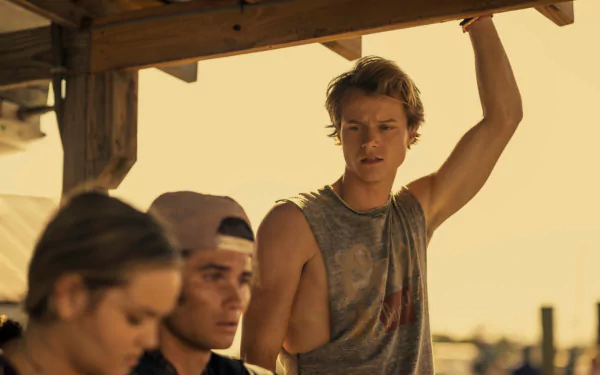 Rudy Pankow from the TV show Outer Banks pictured in a casual sleeveless shirt, featured in a HD PC desktop wallpaper and background.