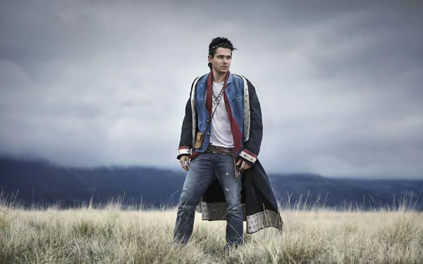 HD desktop wallpaper featuring a man in stylish attire standing in a field with stormy skies overhead.