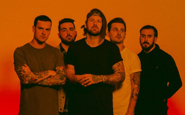 Beartooth band members posing together for an HD desktop wallpaper with an orange background.