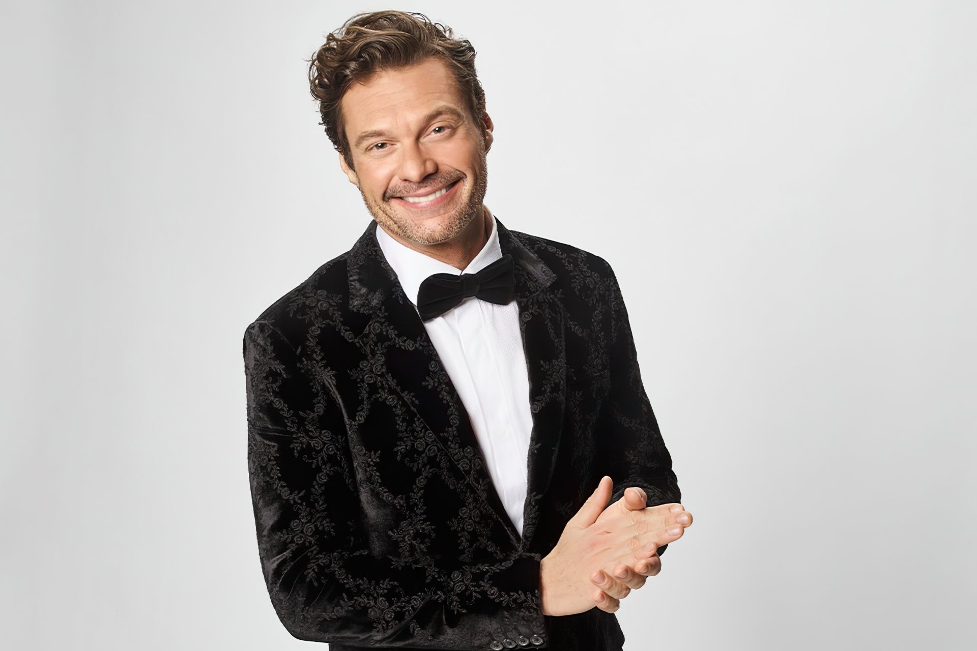 Smiling man in a black velvet tuxedo and bow tie posing for a high-definition desktop wallpaper.