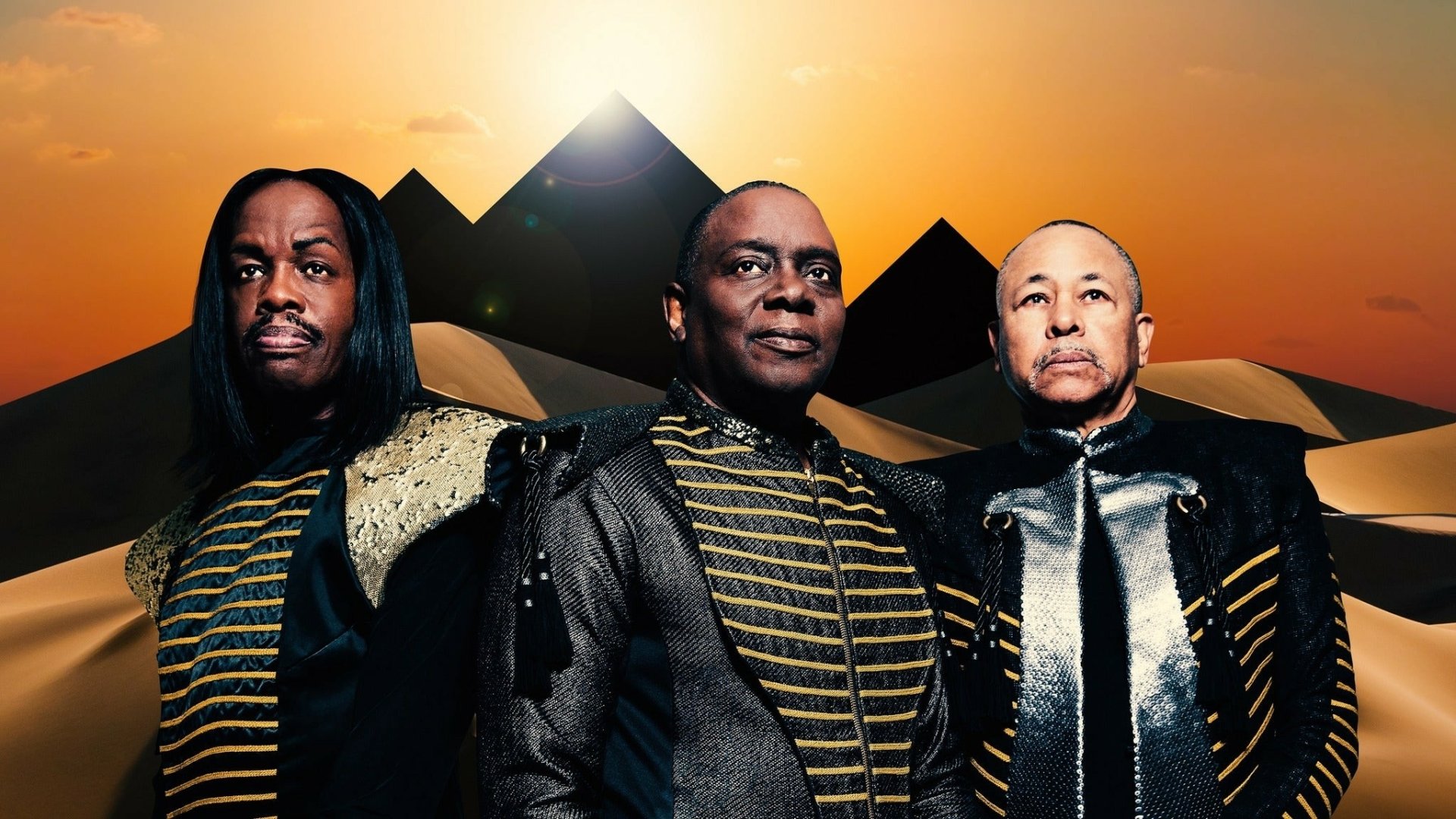 A striking HD desktop wallpaper featuring the iconic band Earth, Wind and Fire against a backdrop of pyramids and a vibrant sunset.