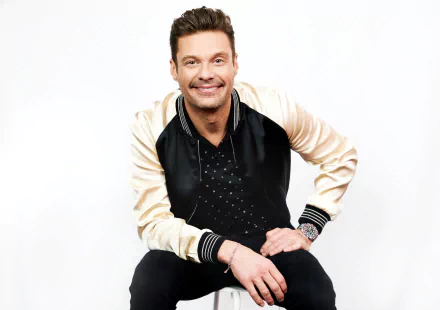 HD wallpaper featuring a smiling person in a stylish black and gold jacket, seated against a white background.