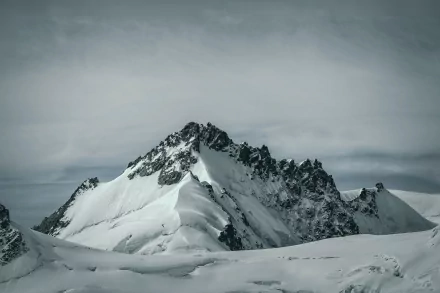 Snow-covered mountain peaks under a cloudy sky, captured in stunning 4K Ultra HD, showcasing the serene beauty of winter nature.