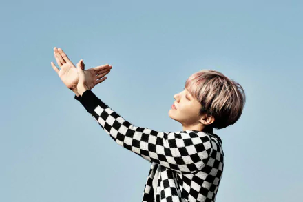 HD desktop wallpaper featuring BTS singer J-Hope (Jung Hoseok) from the K-pop group, posing against a clear blue sky background.