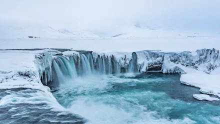 4K Ultra HD image of Iceland’s Goðafoss waterfall surrounded by snow and icy terrain, showcasing pristine nature in a serene winter landscape.