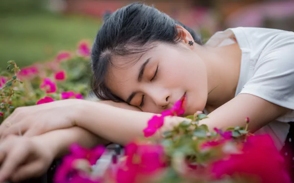 A peaceful Asian woman sleeping among vibrant pink flowers in a serene outdoor setting, captured in 4K Ultra HD for a stunning PC desktop wallpaper.