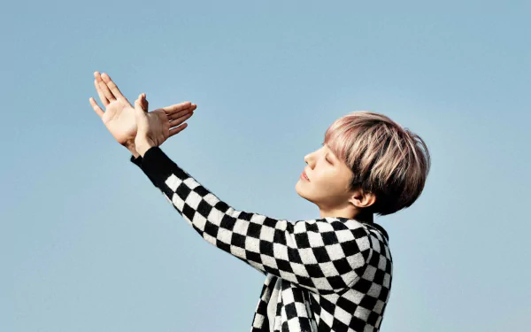 HD desktop wallpaper featuring BTS singer J-Hope (Jung Hoseok) from the K-pop group, posing against a clear blue sky background.