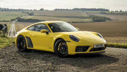 Yellow Porsche 911 Carrera 4S parked on a rural roadside with fields in the background, captured in 4K Ultra HD for a PC desktop wallpaper.