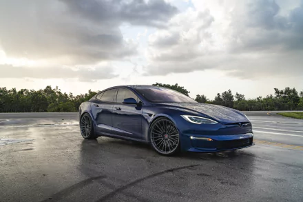 A sleek blue Tesla Model S parked on a wet surface under a cloudy sky, captured in stunning 8K Ultra HD for a dynamic desktop wallpaper and background.