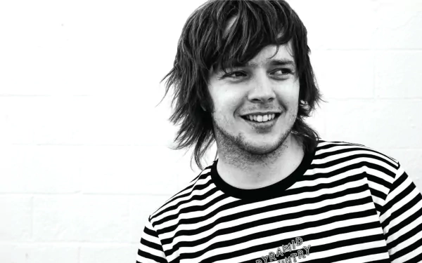 HD desktop wallpaper featuring a smiling man with shaggy hair wearing a striped shirt against a plain background, tagged as Billy Strings.
