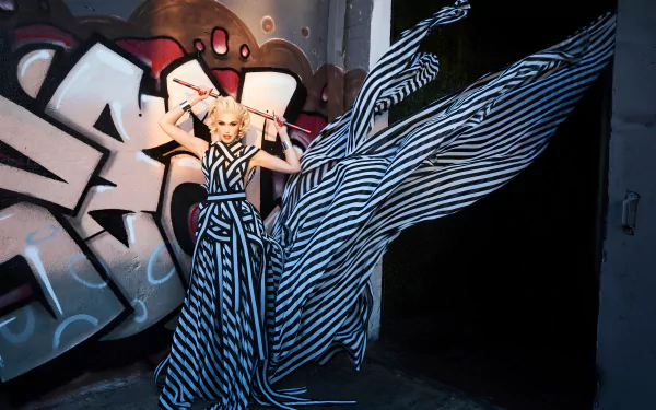 Person in a dramatic black-and-white striped gown posed before graffiti, flowing fabric creating motion — bold music-themed 4K Ultra HD PC desktop wallpaper and background.