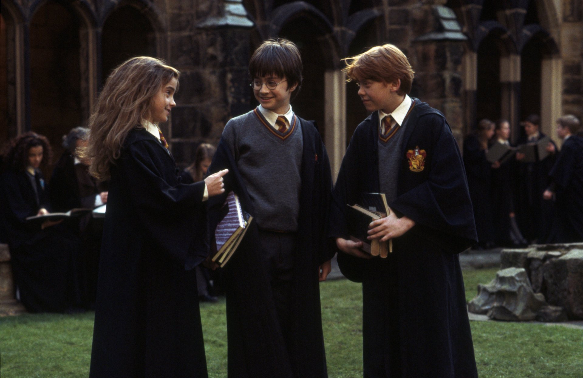 HD desktop wallpaper: Harry, Hermione Granger and Ron Weasley in a Hogwarts courtyard — from the movie Harry Potter and the Philosopher's Stone.