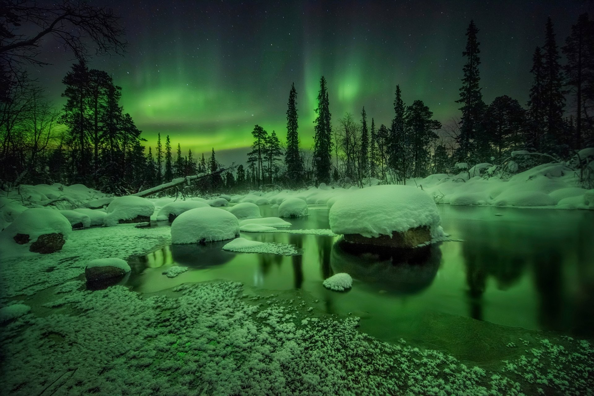 HD desktop wallpaper of a winter night in nature, showcasing the vibrant green aurora borealis above a snowy forest and icy river.