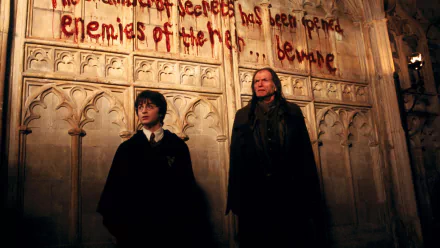 HD desktop wallpaper from Harry Potter and the Chamber of Secrets featuring Daniel Radcliffe as Harry Potter and David Bradley as Argus Filch standing by a warning written on the wall.