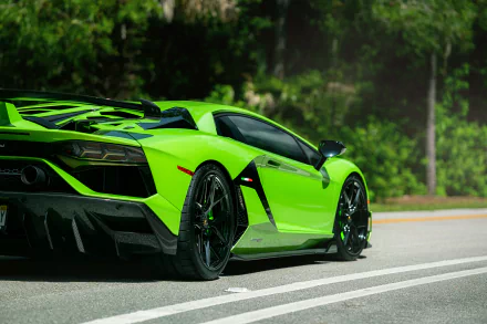 A vibrant green Lamborghini Aventador SVJ parked on a road with lush green trees in the background, captured in stunning 8K Ultra HD for a PC desktop wallpaper.