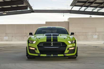 Front view of a lime-green Ford Mustang Shelby GT500 muscle car with black racing stripes in an industrial parking deck — 5K Ultra HD PC desktop wallpaper/background.