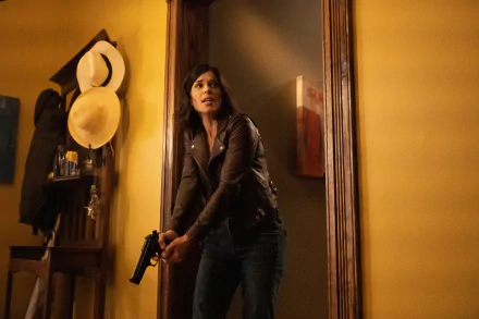 HD desktop wallpaper: woman in a leather jacket gripping a handgun in a tense hallway scene from the movie Scream (2022).