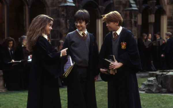 HD desktop wallpaper: Harry, Hermione Granger and Ron Weasley in a Hogwarts courtyard — from the movie Harry Potter and the Philosopher's Stone.