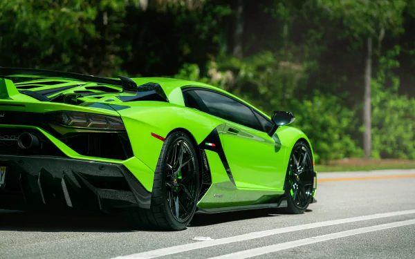 A vibrant green Lamborghini Aventador SVJ parked on a road with lush green trees in the background, captured in stunning 8K Ultra HD for a PC desktop wallpaper.