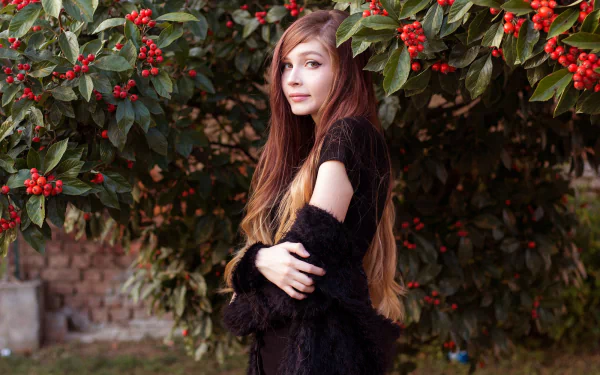 HD PC desktop wallpaper background of a long-haired woman model posing beneath berry-laden branches, wearing a black outfit and gazing toward the camera.