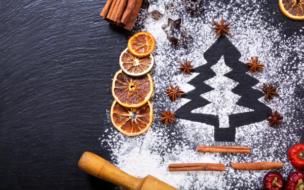 4K Ultra HD PC desktop wallpaper — still-life photography: Christmas tree silhouette dusted with powdered sugar on dark slate, framed by dried orange slices, cinnamon sticks and star anise.
