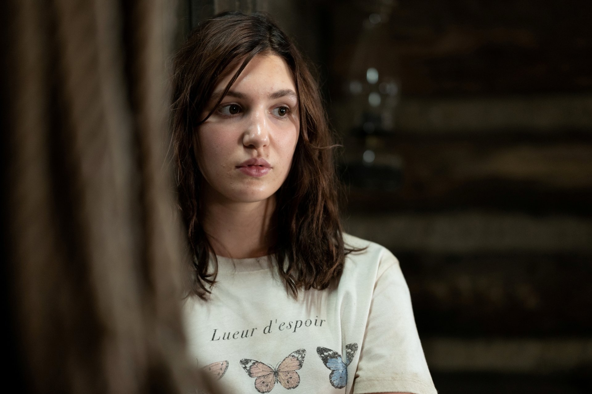 4K Ultra HD PC desktop wallpaper: contemplative young woman in a dim cabin, moody atmosphere evoking the TV show Yellowjackets.