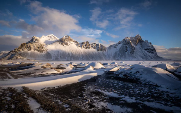 Snow-covered Vestrahorn Mountain in Iceland under a partly cloudy sky, captured in stunning 4K Ultra HD for a vivid nature desktop background.