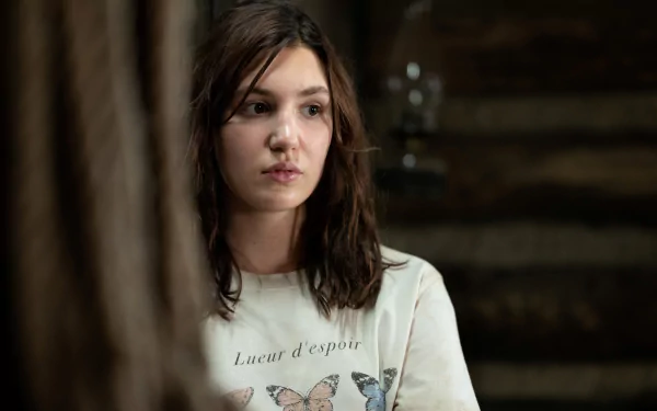 4K Ultra HD PC desktop wallpaper: contemplative young woman in a dim cabin, moody atmosphere evoking the TV show Yellowjackets.