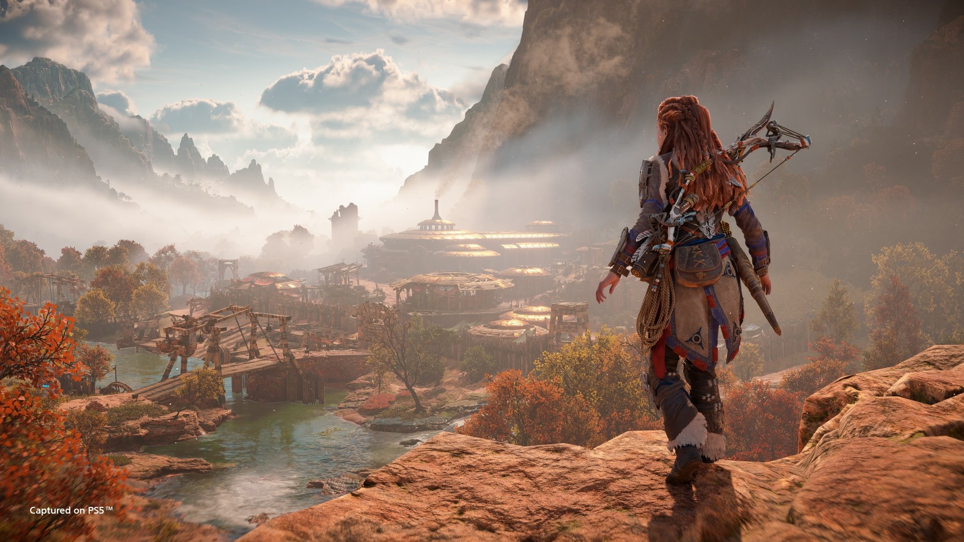 Aloy from Horizon Forbidden West stands on a rocky cliff overlooking a vast, detailed landscape in this 4K Ultra HD PC desktop wallpaper from the Horizon video game series.