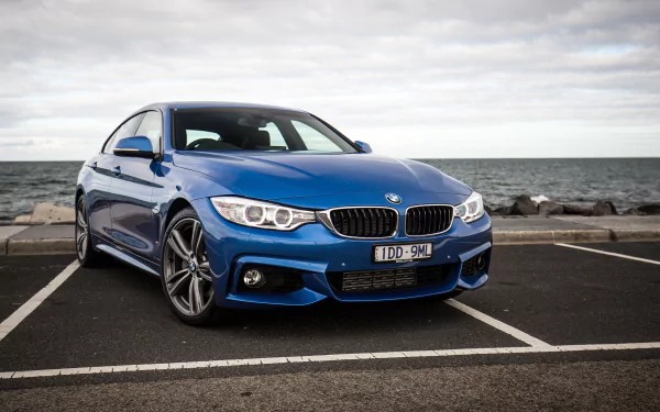 Blue BMW 4 Series parked by the sea, captured as a 2K Quad HD PC desktop wallpaper and background.