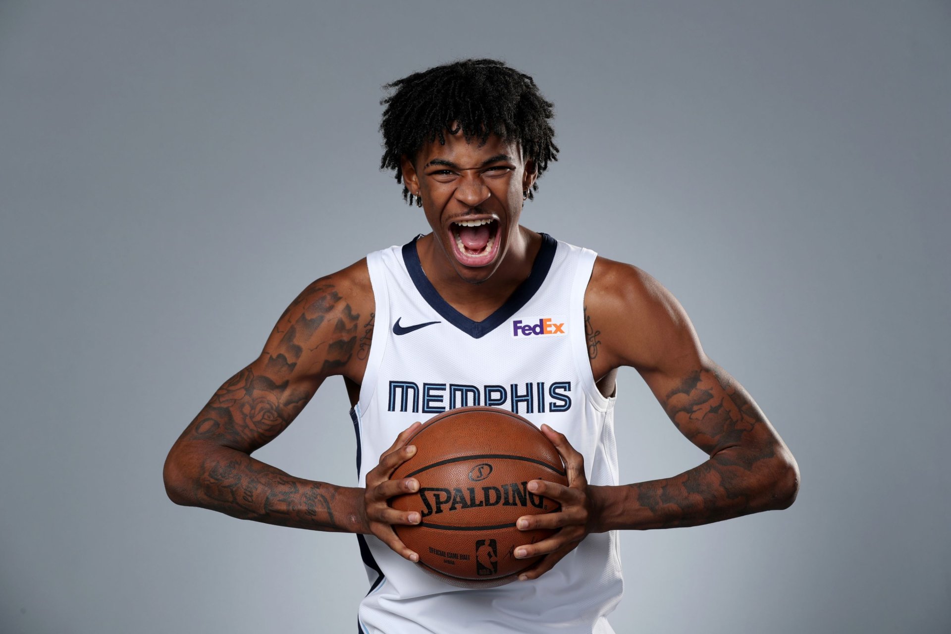 HD PC desktop wallpaper featuring NBA player Ja Morant in a Memphis jersey holding a basketball with an intense expression against a plain gray background.