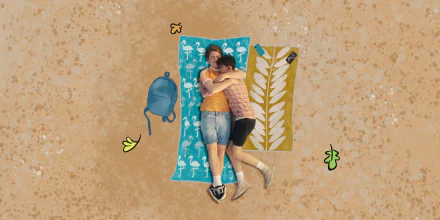 HD desktop wallpaper featuring characters from the TV show Heartstopper lying on colorful towels against a sandy background with scattered backpack and leaves.