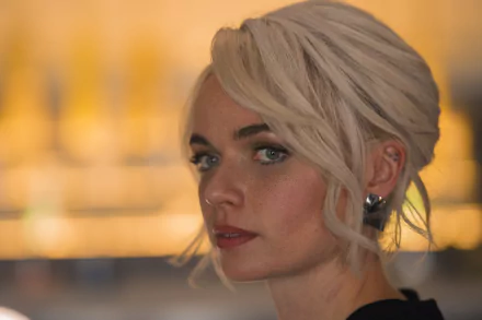 Close-up of a blonde woman with an elegant updo in warm, cinematic lighting — sci‑fi TV character portrait, 2K Quad HD PC desktop wallpaper.