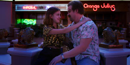 HD PC desktop wallpaper featuring a scene from the TV show Stranger Things with two characters sharing a moment outside a neon-lit Orange Julius.