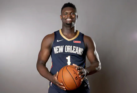 Zion Williamson poses confidently in his New Orleans jersey, holding a basketball. This HD desktop wallpaper captures the essence of sports and athleticism.