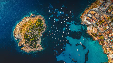Aerial 4K Ultra HD PC desktop wallpaper of a Spanish island and coastal town: rocky tree-covered islet beside turquoise waters dotted with anchored boats.