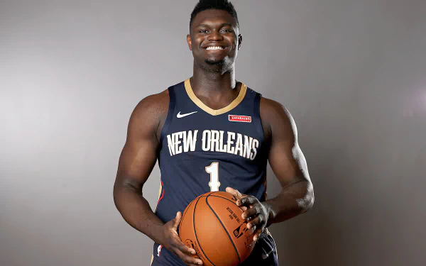 Zion Williamson poses confidently in his New Orleans jersey, holding a basketball. This HD desktop wallpaper captures the essence of sports and athleticism.